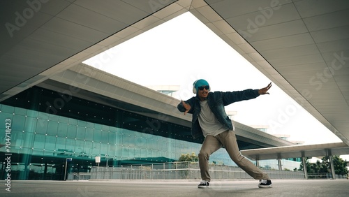 Motion shot of happy hipster practice b boy dance with stylish cloth at building. Dancer enjoy show footstep performance. Modern lifestyle, break dancing. Slow motion. Outdoor sport 2024. Sprightly. © Summit Art Creations