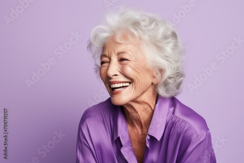 Emotional senior woman. Portrait of beautiful senior woman laughing while standing against purple background