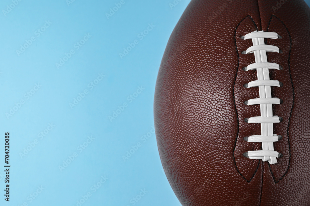 American football ball on light blue background, top view. Space for text American football ball on light blue background, top view. Space for text