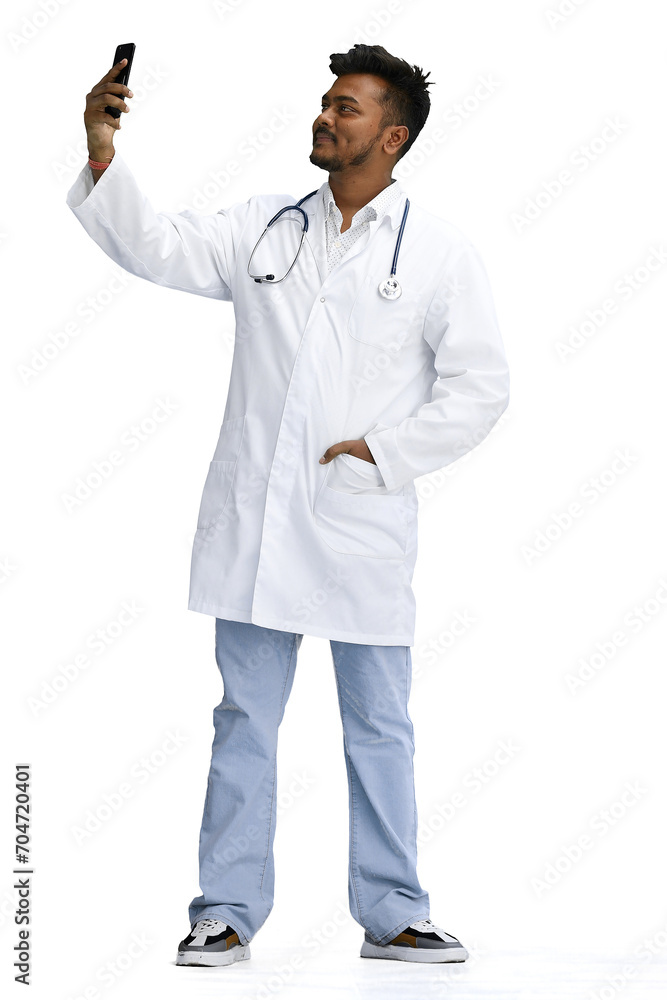 A male doctor, on a white background, in full height, talking on the phone A male doctor, on a white background, in full height, talking on the phone