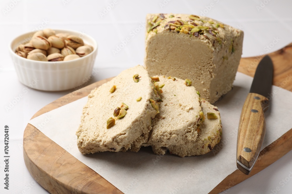 Tasty halva with pistachios and knife on white table, closeup Tasty halva with pistachios and knife on white table, closeup