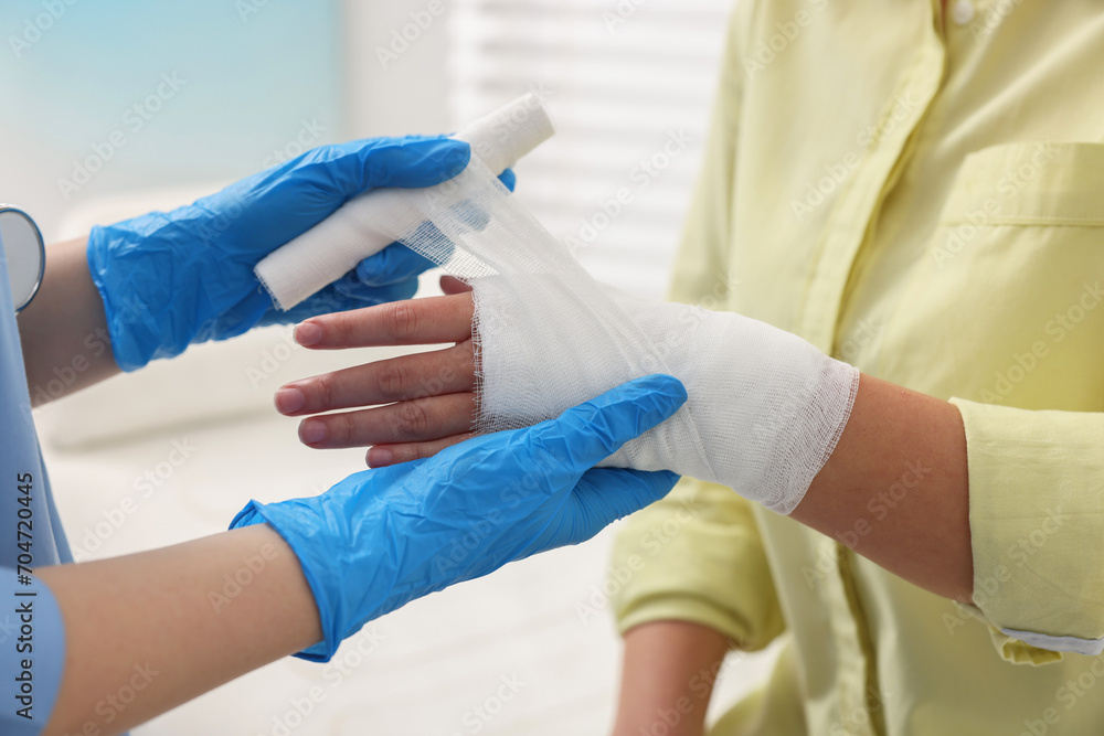 Doctor bandaging patient's burned hand in hospital, closeup Doctor bandaging patient's burned hand in hospital, closeup