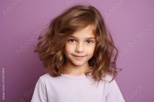 Portrait of a cute little girl with long curly hair on a purple background. © Chacmool