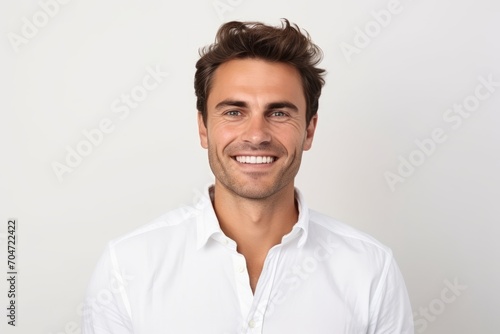 Portrait of handsome young man in white shirt smiling at camera.