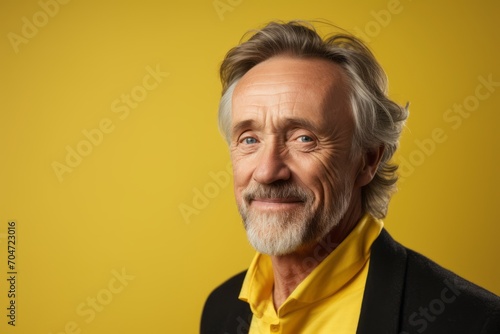 Portrait of a smiling senior man looking at the camera over yellow background