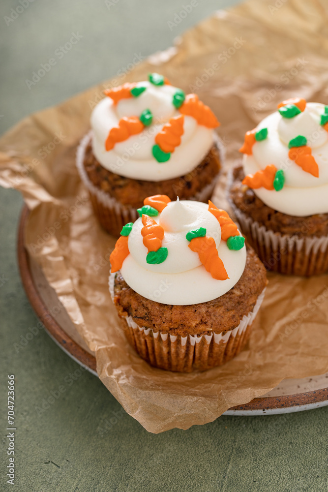 Carrot cake cupcakes with cream cheese frosting decorated with little carrots