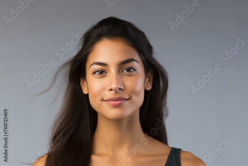 Portrait of a beautiful young woman with long hair on grey background