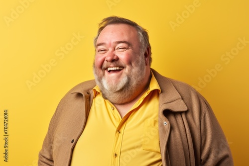 Portrait of a happy senior man laughing at the camera over yellow background © Chacmool