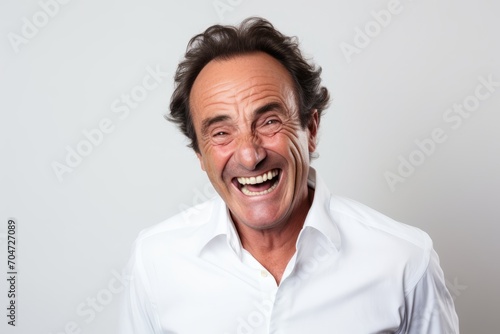 Portrait of a senior man laughing against a grey background with copy space