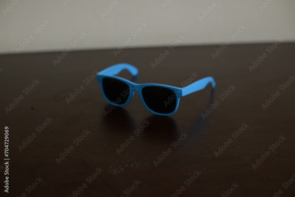 Óculos escuro azul em cima da mesa do quarto aberto - obrazy, fototapety, plakaty 