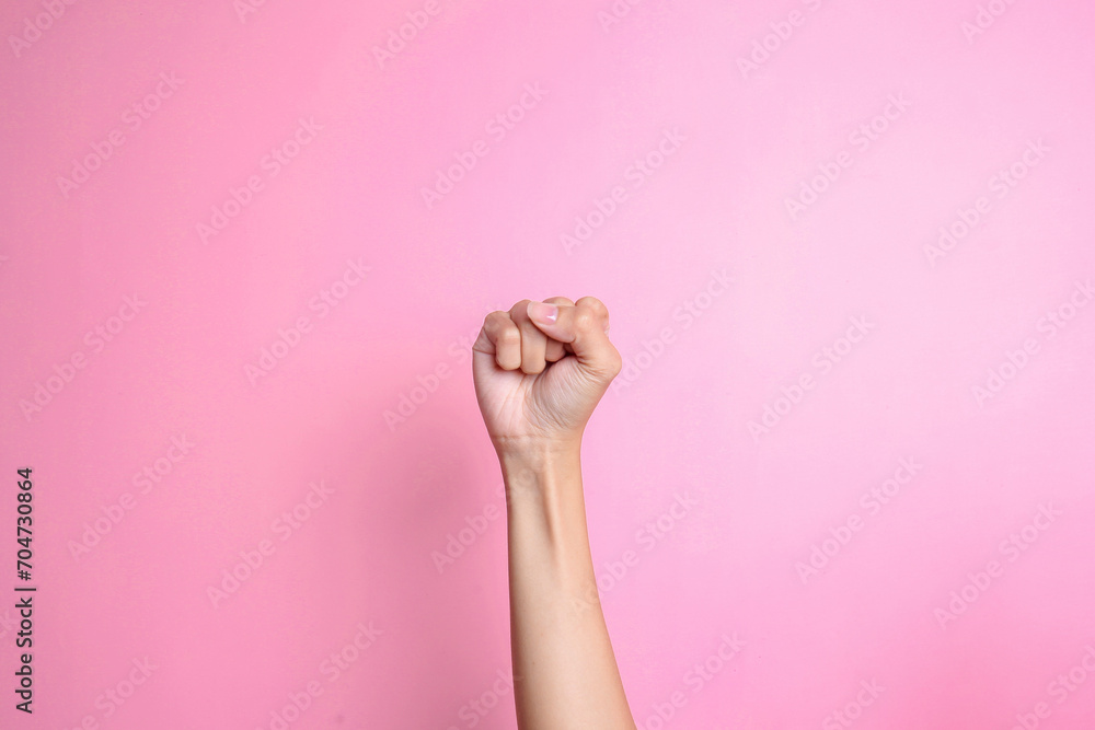 Hand showing fist or punching air over pink background. Protest symbol - obrazy, fototapety, plakaty 