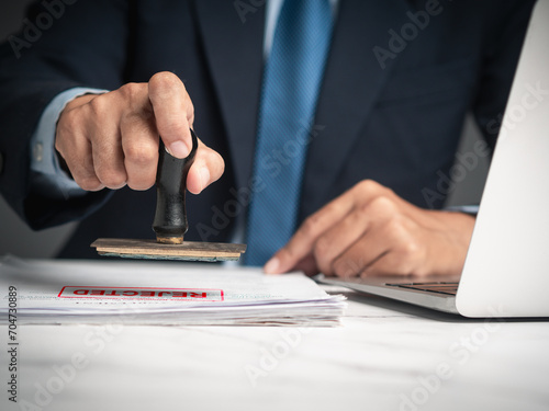 Photos Businessman stamped for rejected documents while sitting at a desk in the office