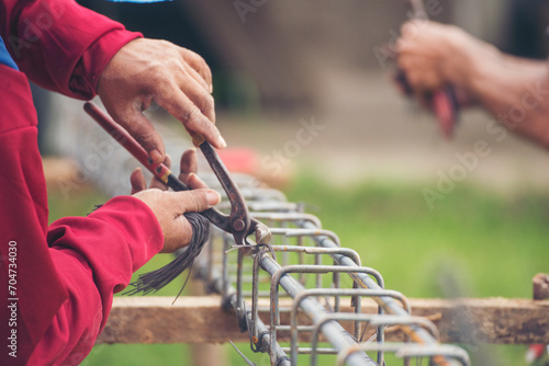 Construction Worker hands using pincer pliers iron wire. Outdoor Worker using wire bending pliers, construction work. Men hands bending cutting steel wire fences bar reinforcement of concrete work