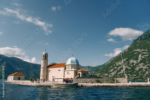 Group of tourists stands on the island of Gospa od Skrpjela near a moored boat. Montenegro photo