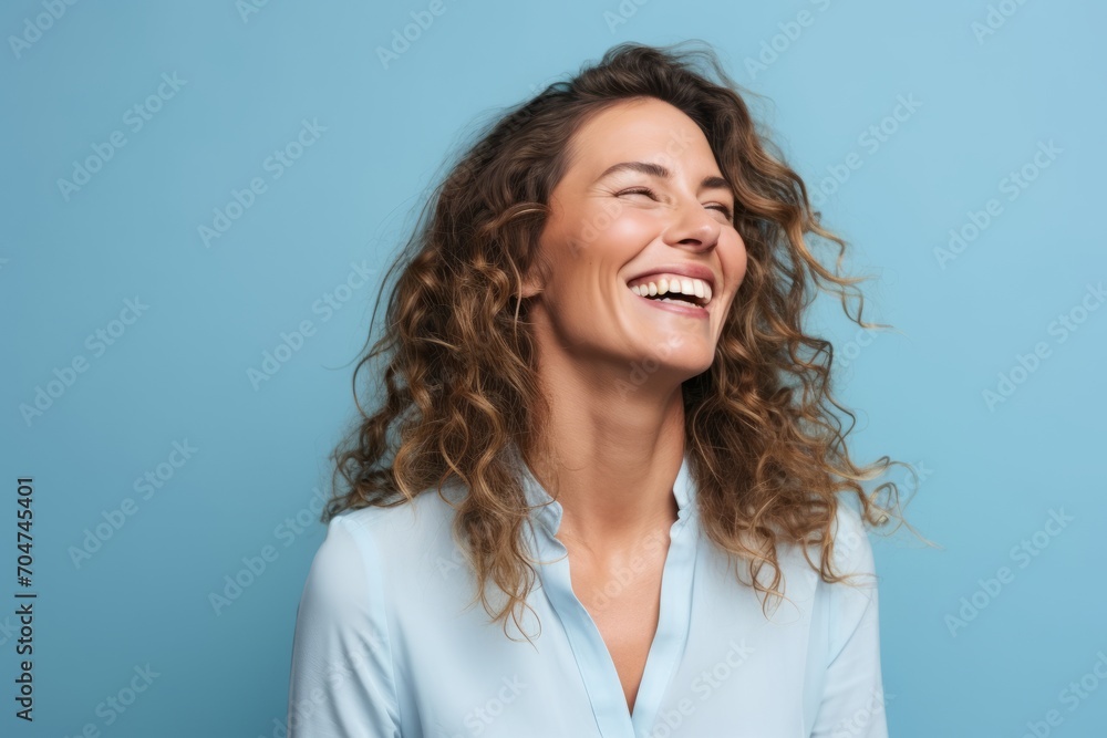 Portrait of happy young woman laughing and looking up isolated over blue background Portrait of happy young woman laughing and looking up isolated over blue background