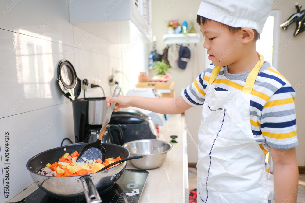 Cute happy smiling Asian 8 years old boy child wearing chef hat and apron having fun preparing, cooking healthy Homemade Japanese Curry Rice at home, Little home helper, EF skill development concept Cute happy smiling Asian 8 years old boy child wearing chef hat and apron having fun preparing, cooking healthy Homemade Japanese Curry Rice at home, Little home helper, EF skill development concept