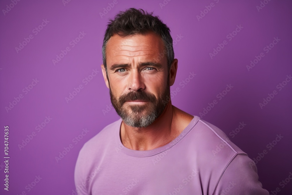 Portrait of handsome mature man with beard and mustache looking at camera while standing against purple background Portrait of handsome mature man with beard and mustache looking at camera while standing against purple background