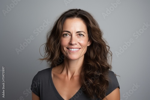 Portrait of a smiling woman with long wavy hair against grey background photo