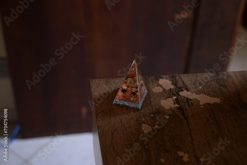 Pirâmide como peso de papel translucida em cima da mesa de madeira