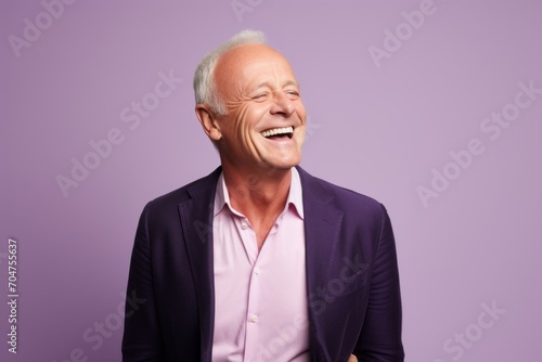 Portrait of happy senior man laughing and looking at camera on violet background