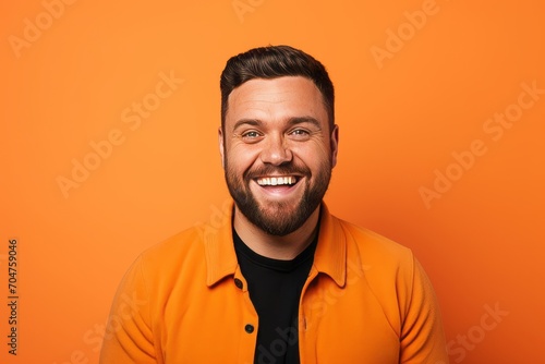 Portrait of a happy young man laughing on an orange background.