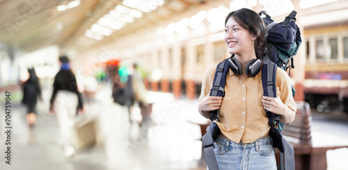 Obraz na plátně Young woman traveler with backpack waiting for train, Asian backpacker on railway platform at train station