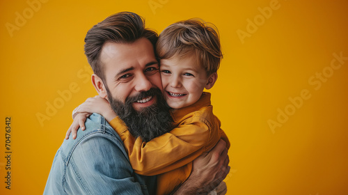 Cute boy hugging his dad on yellow background, Fathers Day concept. © Jammy Jean