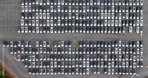 Aerial view of a new car lot, neatly arranged vehicles reflecting uniformity and precision, symbolizing organized commerce and transportation.