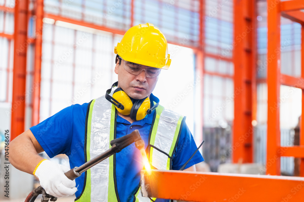Man worker welder welding steel structures inside buildings of industrial plants in construction site. Male technician working welding iron with sparks at metalwork.