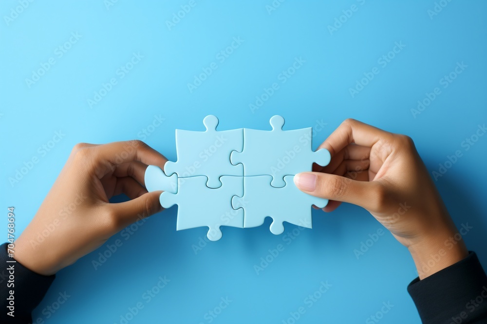 Four blue puzzle pieces being put together by two hands