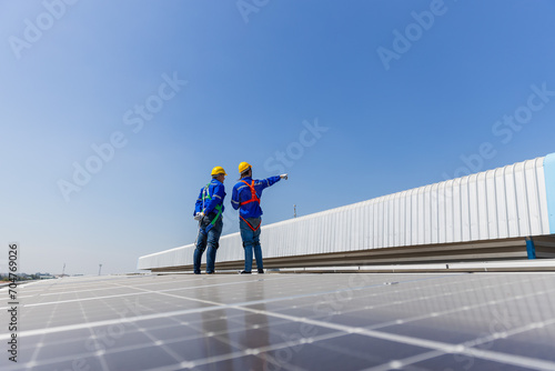 Technicians are inspecting standards of solar panels on roof of an industrial factory. Electrical energy obtained from nature sunlight clean renewable energy.