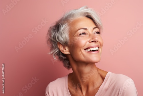 Portrait of a beautiful senior woman smiling at the camera over pink background