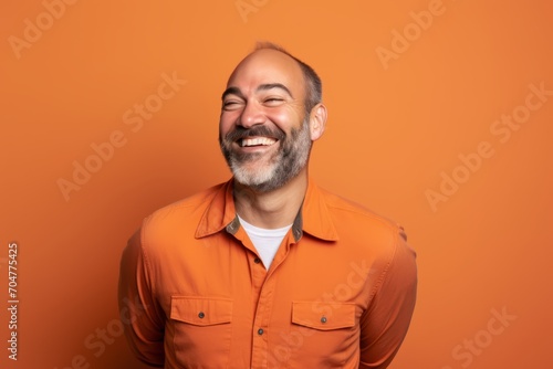 Portrait of a happy senior man in orange shirt on orange background
