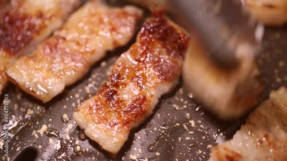 잘라진 생삼겹살을 집게로 뒤집어 가며 굽는 잘라진 생삼겹살을 집게로 뒤집어 가며 굽는