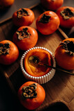 Ripe persimmons on wooden cutting board on black marble background