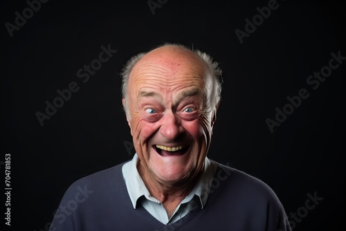 Senior man with funny expressions on a black background. Studio shot. © Inigo
