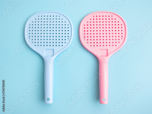 A blue and a pink pickleball paddle on a teal background.