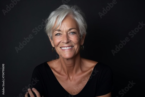 Portrait of a happy senior woman smiling on black background with copy space