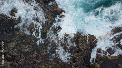 Drone view of Atlantic ocean with strong swell beating against the rocky cliff in Tenerife south coast, blue rough sea with big waves with foam crashing against the rocks, Canary island © luciano