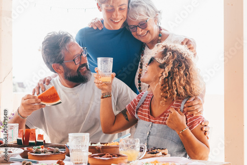 Beautiful happy multigenerational family having lunch together on the terrace at home. Parents, son and grandmother smile enjoying closeness and free time photo