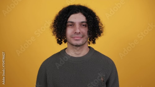 Positive curly man nodding head, say yes, showing approving gesture, body language concept. Indoor studio shot isolated on yellow background. People lifestyle concept. photo