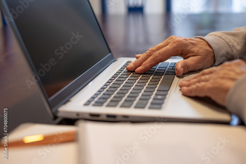 Close-up on female mature hands typing on laptop keyboard, old people using new technologies