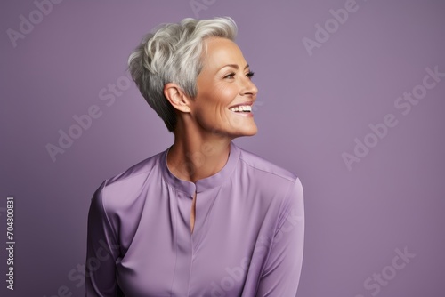 Beautiful smiling middle aged woman with short grey hair in purple shirt