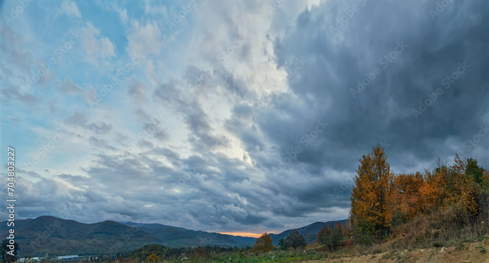 Dramatic, sunset cloudy sky over autumn country landscape