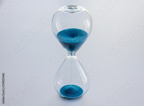 Hourglass containing blue sand isolated on white background