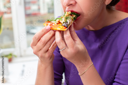 Woman s hands hold a piece of pizza in her hand.Eating pizza