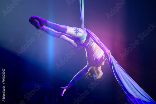 Performance by a circus acrobat artist. Girls perform aerial acrobatic elements on fabric.