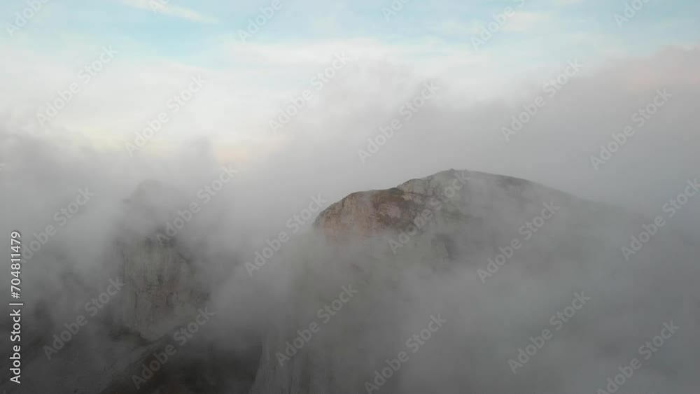 Aerial flyover through clouds with view of Tour d'Aï and Tour de Mayen in Leysin, Vaud, Switzerland with a colorful alpenglow on the Swiss Alps in the background Aerial flyover through clouds with view of Tour d'Aï and Tour de Mayen in Leysin, Vaud, Switzerland with a colorful alpenglow on the Swiss Alps in the background
