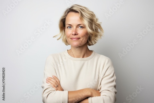 Portrait of a blonde woman with crossed arms on a gray background