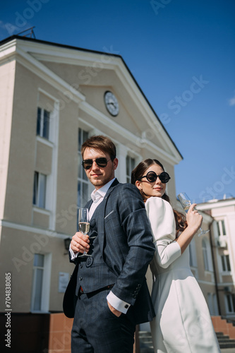 A man and a woman holding wine glasses. They are both standing and appear to be dressed formally, possibly